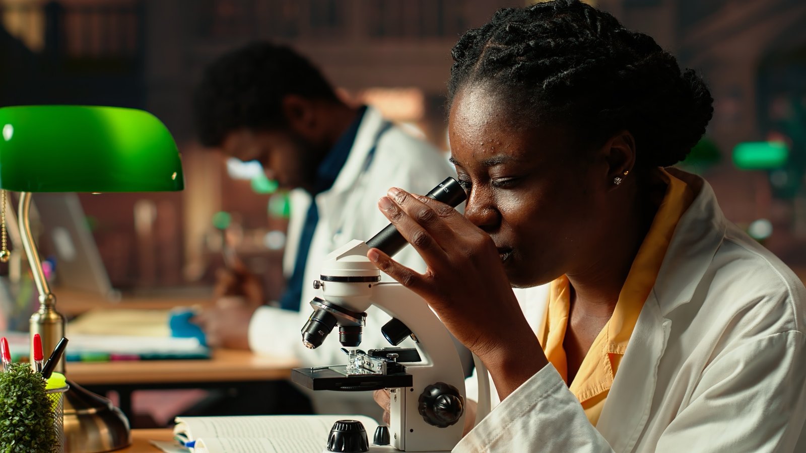 Étudiante en blouse blanche observant un échantillon au microscope